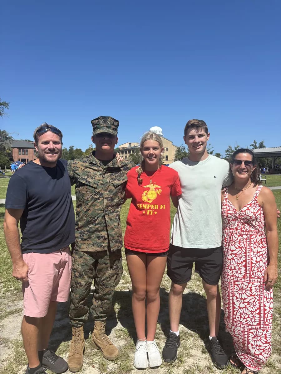 Brent with family members, including a U.S. Marine in camouflage uniform, on a sunny day