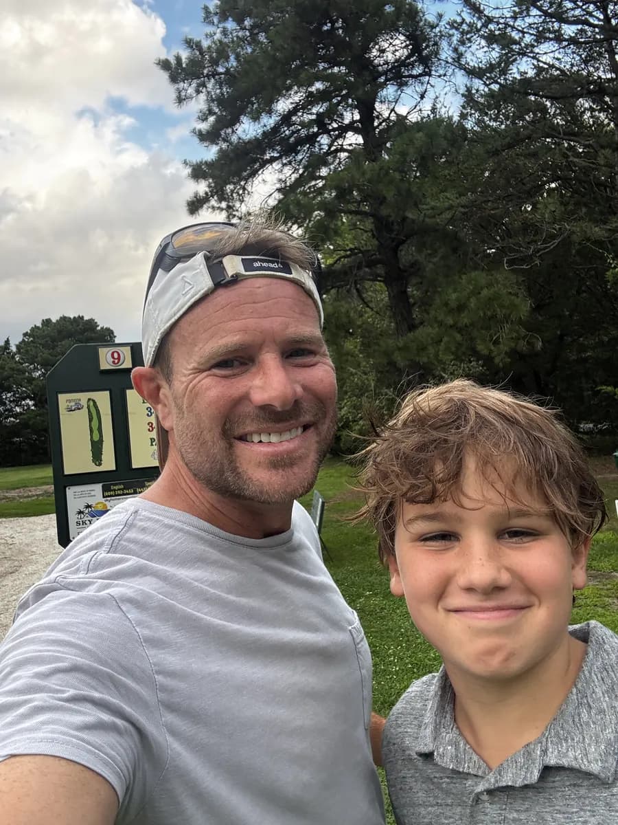 Brent smiling in a selfie with a young boy in front of pine trees