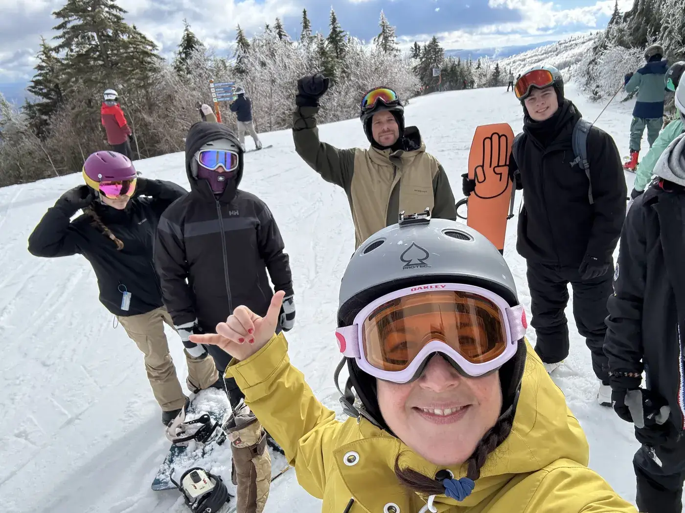A group of snowboarders in goggles and helmets posing on a snowy slope
